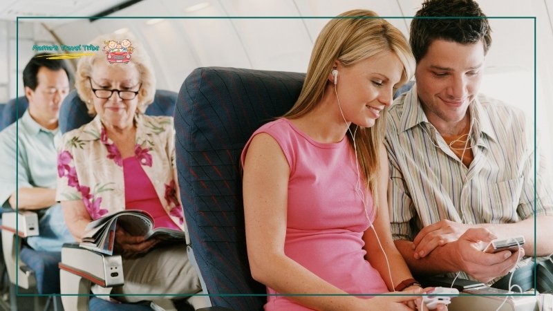 A couple with earphones looking at something on their phones happily and an older woman in the back seat reads a magazine with her glasses own. Engaging in activities and keeping busy on the plane. is it safe to fly in the rain. 