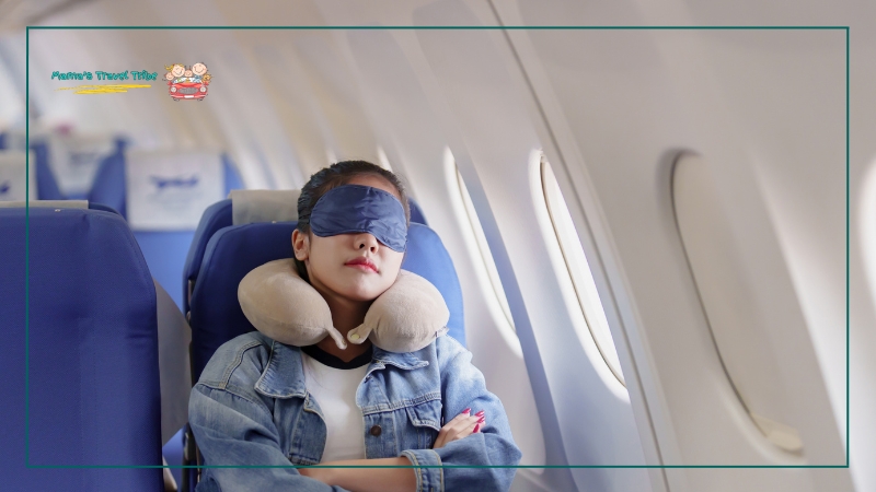 woman sleeping on plane with an eye mask and pillow around neck. how to make a bed on a plane. 