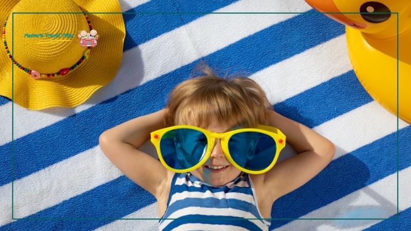 Beach resort, child lying on a beach blanket. places to go with 2 year olds.