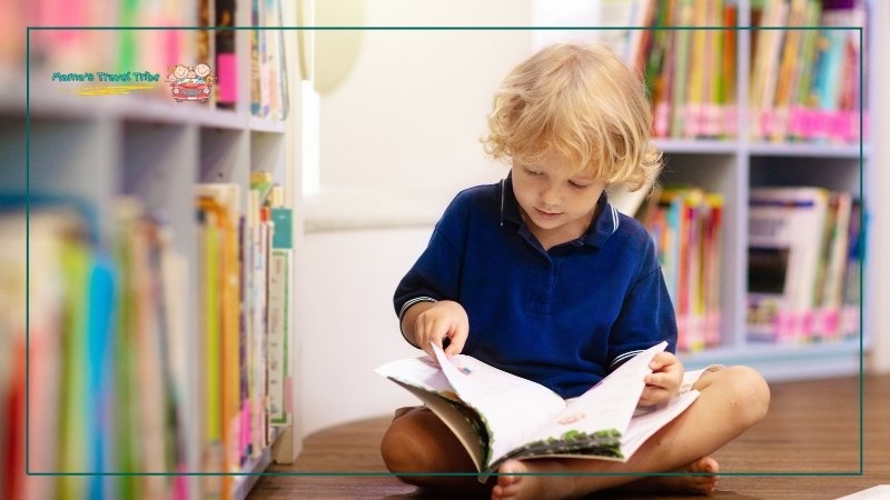 places to go with 2 year olds. 2 year old sitting on the library floor and reading a book barefoot.