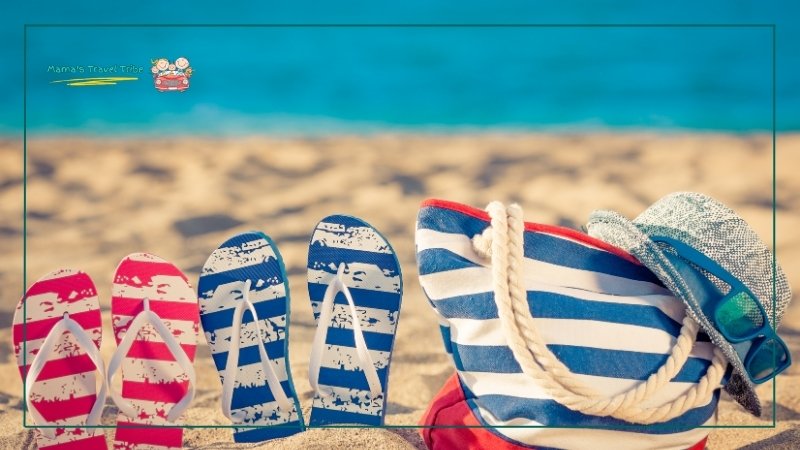 water slippers, sunglasses, sun hat and beach bag on the beach. toddler beach essentials