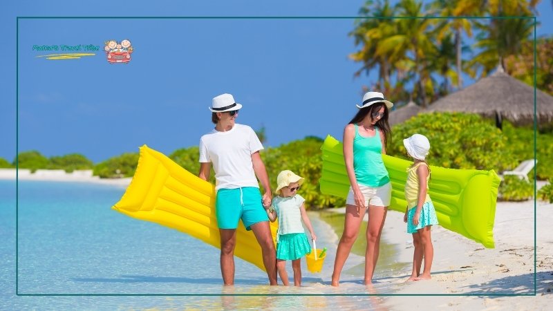 family of 4 in colour coordinated outfits holding floaters by the beach. toddler beach essentials