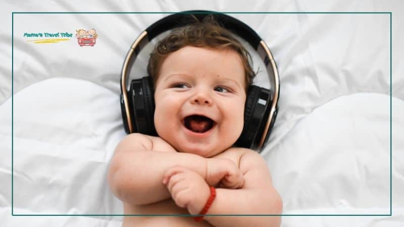 baby lying on bed laughing with headphones. Do Babies Need Headphones on Planes