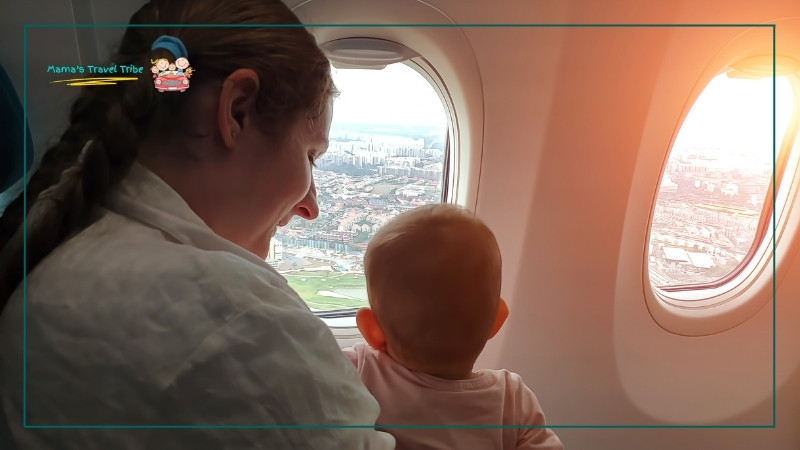 tips for flying with a 1 year old. mother and baby looking out of airplane window.