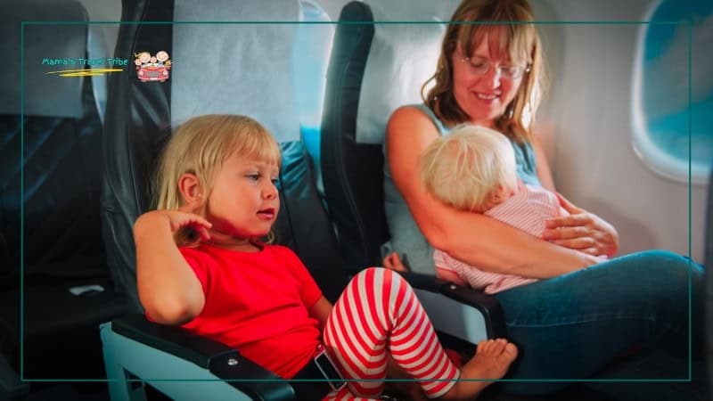 Toddler on separate seat in plane and baby in mom's arms. How to keep a baby comfortable on the plane. Flying With Kids: The Complete Air Travel Guide for Babies and Toddlers