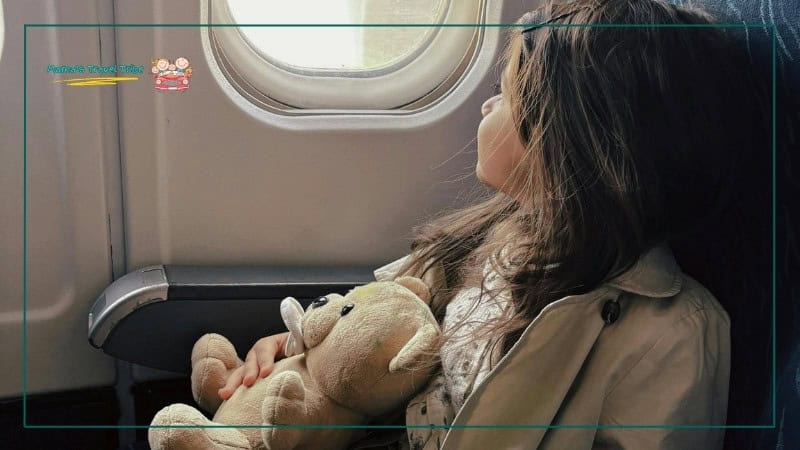 child sitting on separate seat in plane and looking out the window. Should your child fly as a lap infant or in their own seat