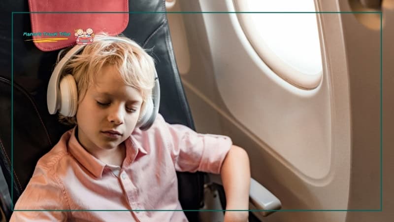 child sleeping on plane with headphones on. Flying With Kids: The Complete Air Travel Guide for Babies and Toddlers. 