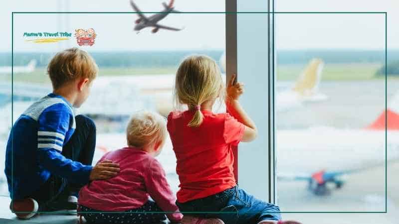 children at the airport looking outside the window with airplanes flying and grounded. Traveling by air with a baby or toddler. Traveling With a Baby and Toddler: Parent Guide
