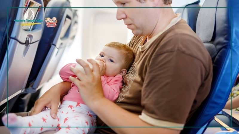 Small. baby having milk on plane with father. Flying With Kids: The Complete Air Travel Guide for Babies and Toddlers.